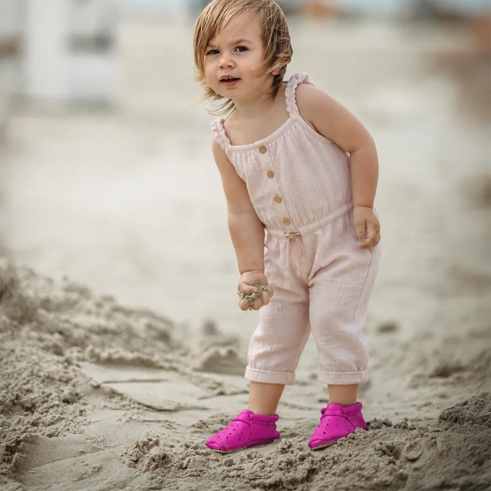 Lieblinge ökologische Kinderschuhe AIRIES für Laufstarter. Süßes Mädchen am Strand mit Lauflernschuhen aus Naturleder in magenta #farbe_magenta