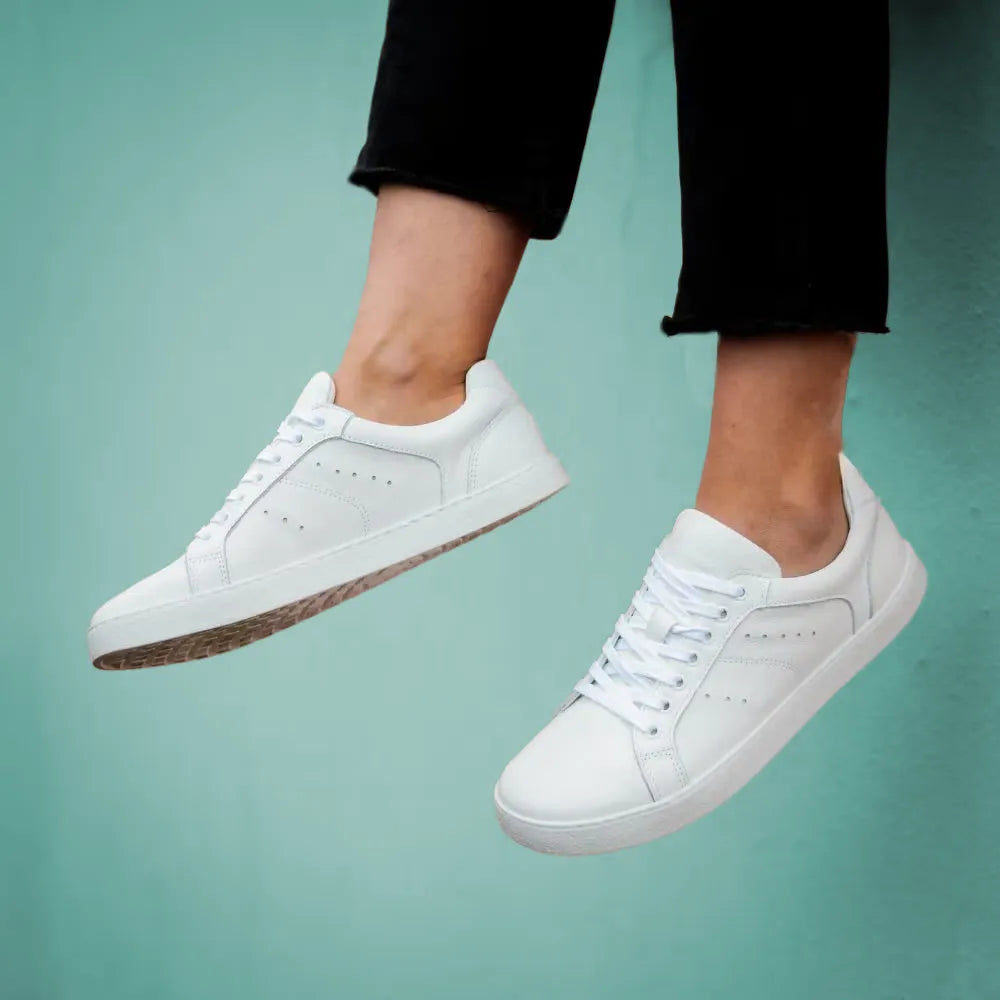 Lieblinge Barfußschuh für Erwachsene in Berlin. Besuche unsere Barfußschuh-Werkstatt und Store in Berlin Prenzlauer Berg. Junger Mann trägt den Universe Barfuß Sneaker in weißem Leder.