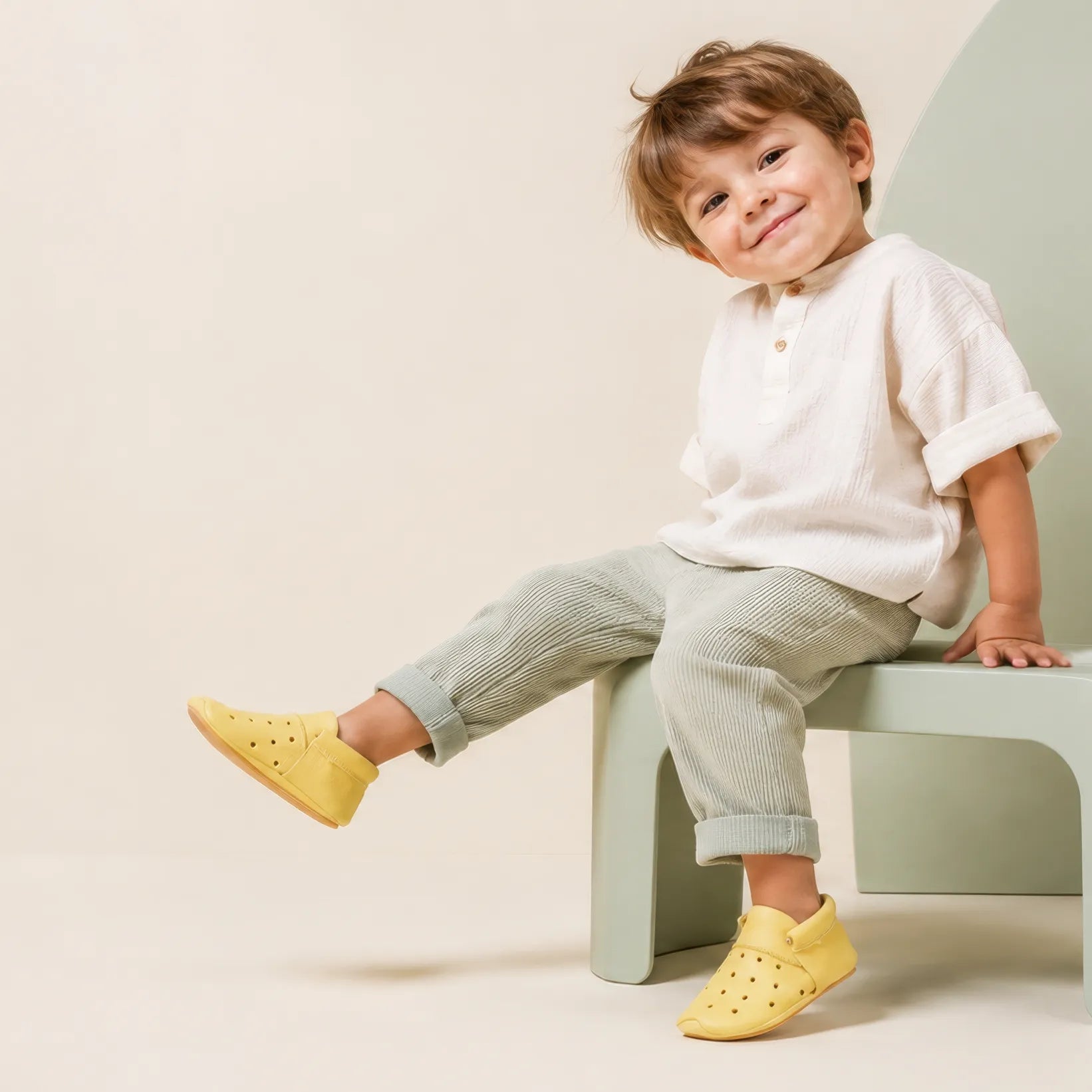 Kind mit gelben Lieblinge-Barfußschuhen auf grünem Hocker