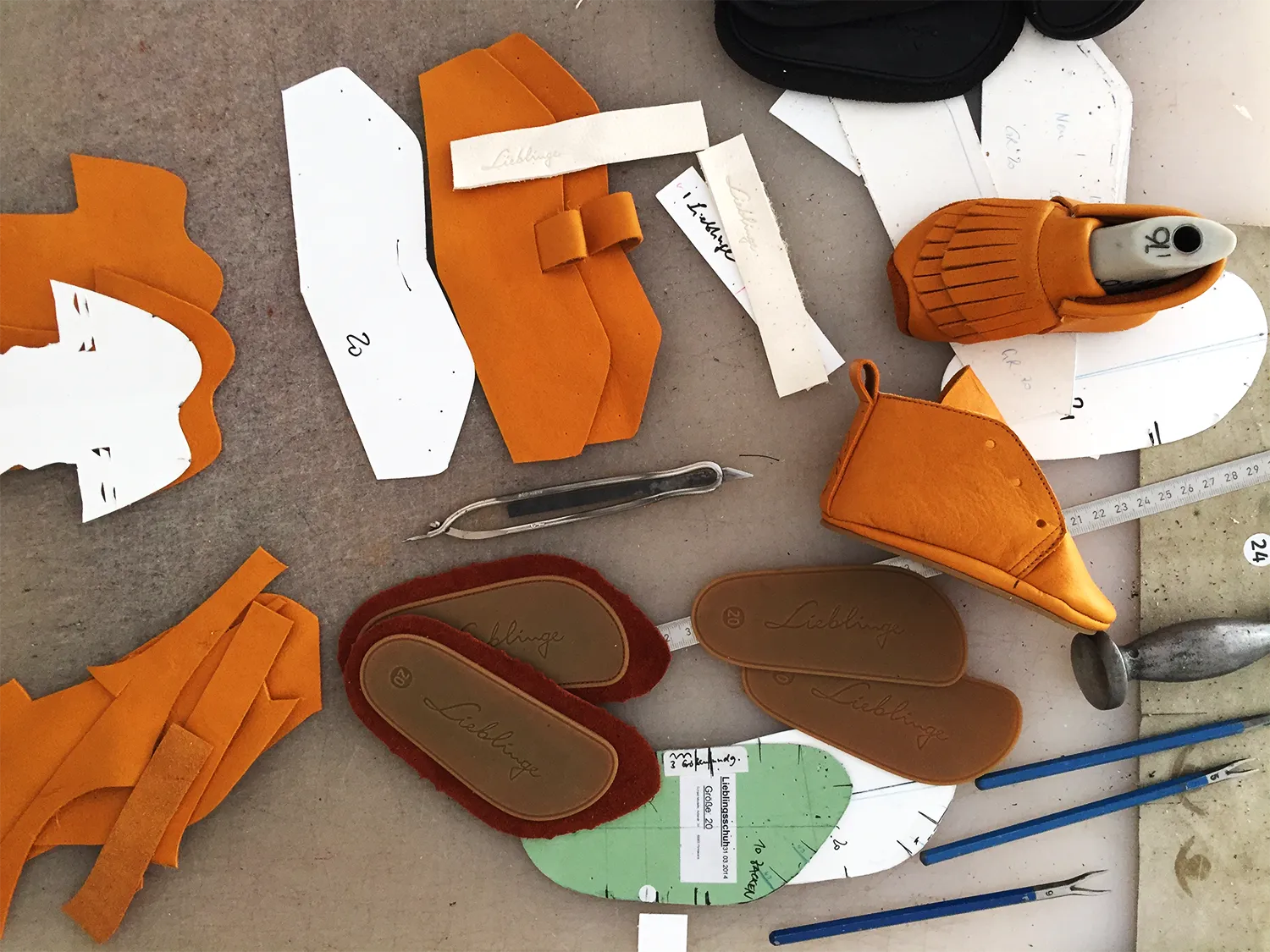 Handarbeit — Schuhe von Lieblinge entstehen: Leisten, Leder, Sohlen und Werkzeug auf dem Werktisch